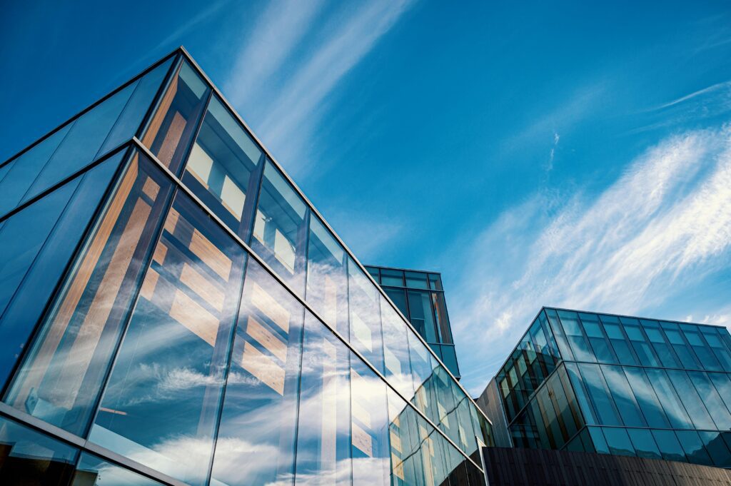 Bâtiment corporatif moderne en verre reflétant le ciel bleu et les nuages