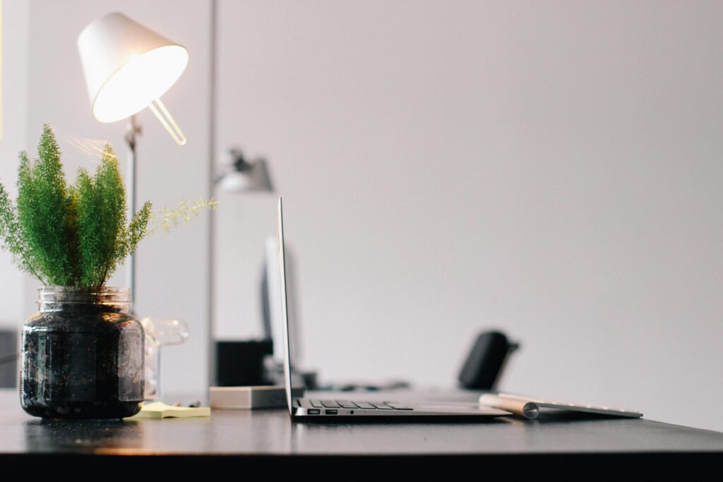 Bureau de partenaire financier chez Groupe Joly Financier Conseil avec un ordinateur portable, une lampe et une plante verte